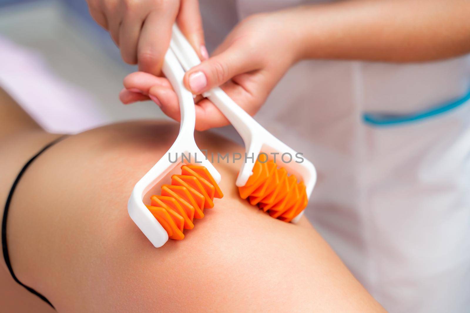 The masseur makes anti-cellulite massage using a roller massager. Physiotherapy and rehabilitation treatment