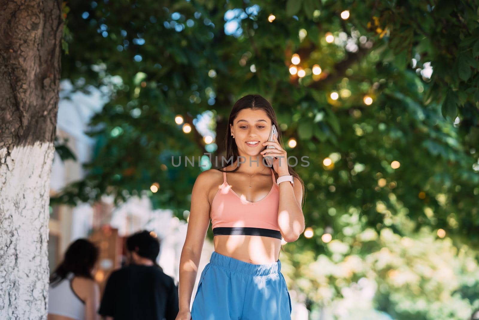 Attractive brunette woman talking on mobile phone on a summer street.