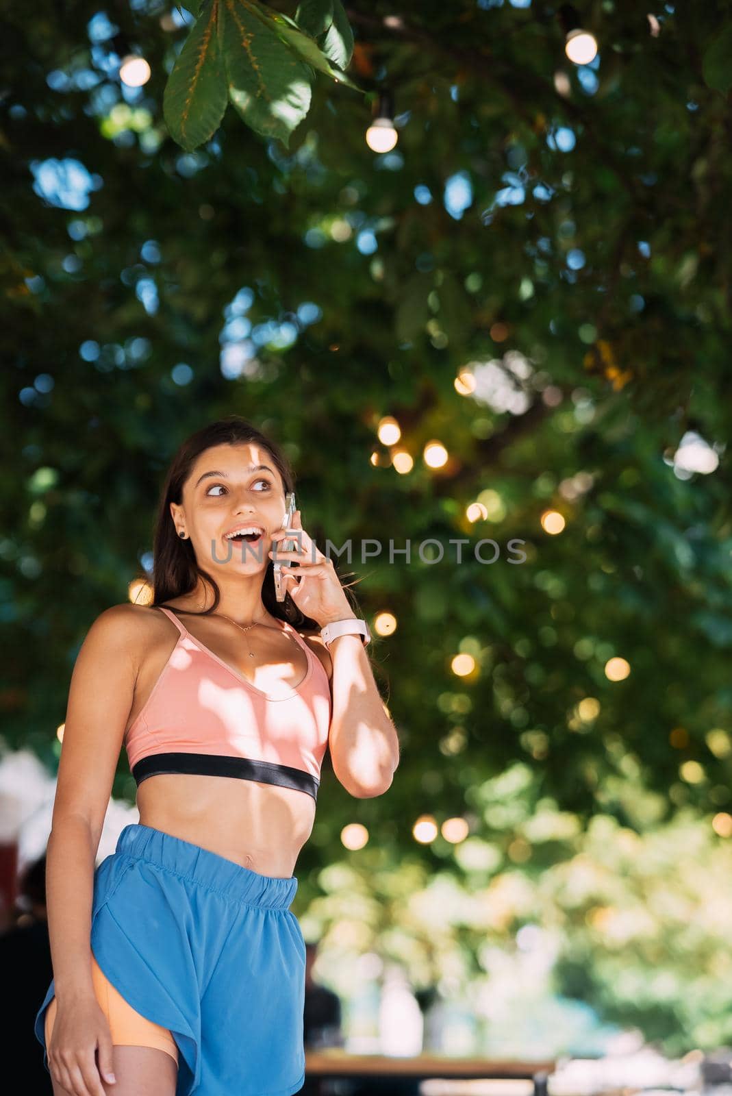 Attractive brunette woman talking on mobile phone on a summer street.