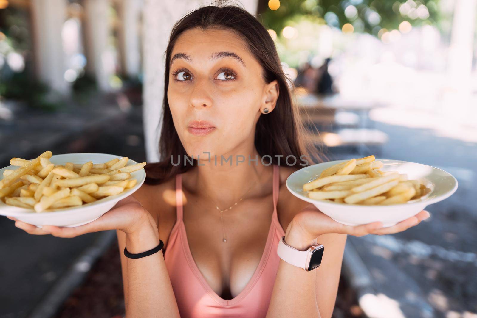 Women hold french fries on white plates. Street cafe