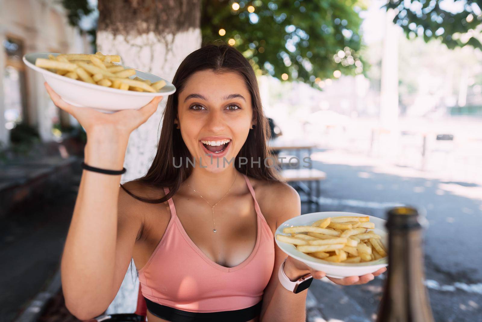 Women hold french fries on white plates. Street cafe