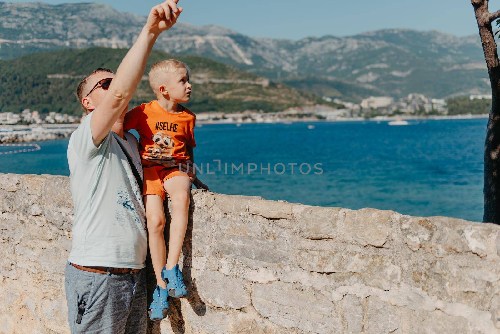 Cute family are having fun on the beach. Father and child against the background of the blue sea and sky. Travel, active lifestyle, vacation, rest concept. a man with a child on the shore. tourists on the shore of Budva, Montenegro.