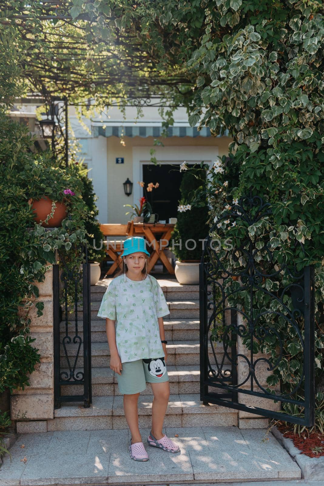 Girl standing in the entrance to the back yard. A beautiful cozy courtyard, a girl stands near the entrance to a beautiful courtyard.