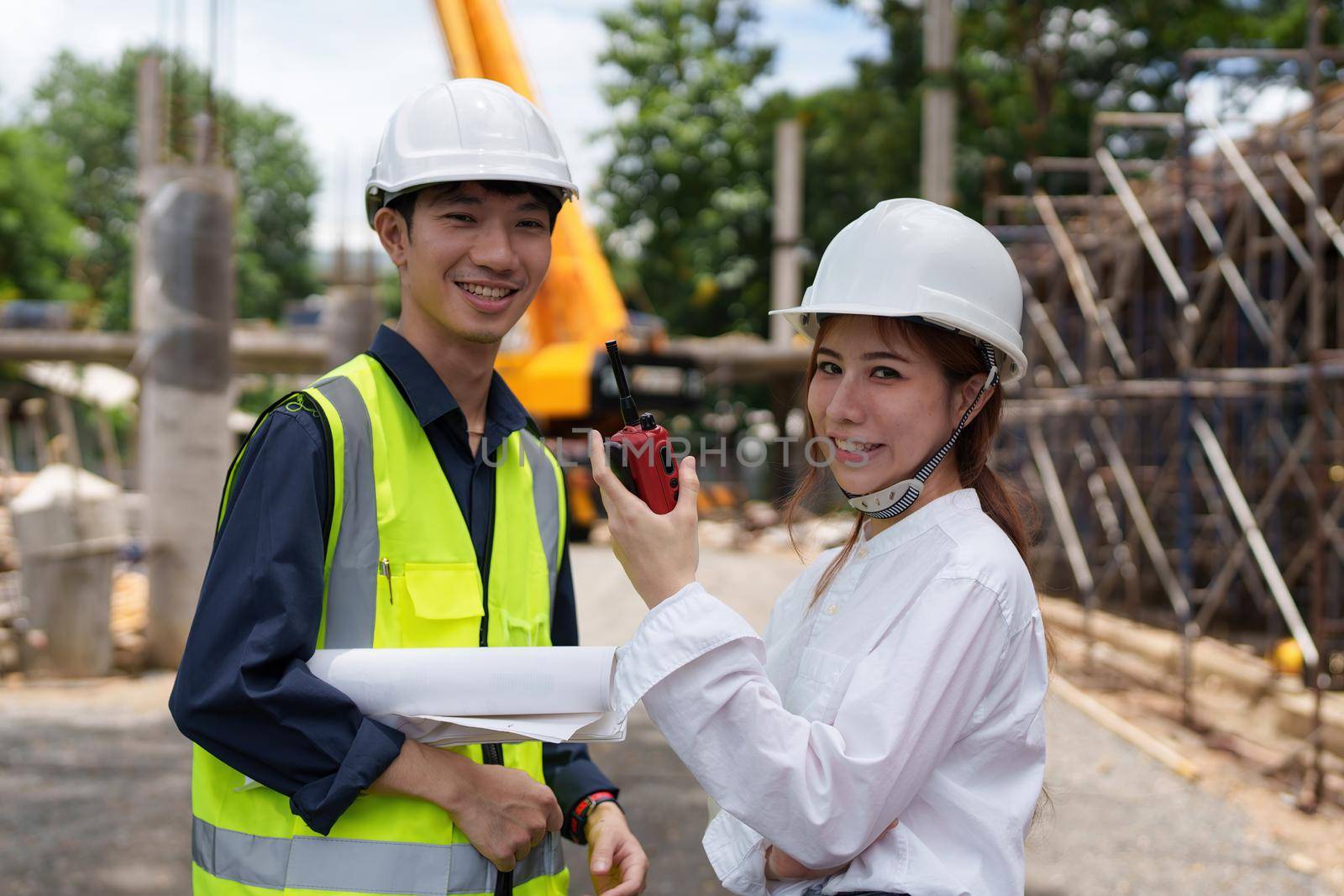 Structural engineer and architect discussing and working with blueprints at the outdoors construction site.