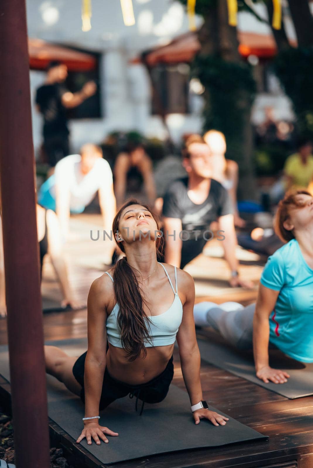 A woman does yoga together with her group in the open air by teksomolika