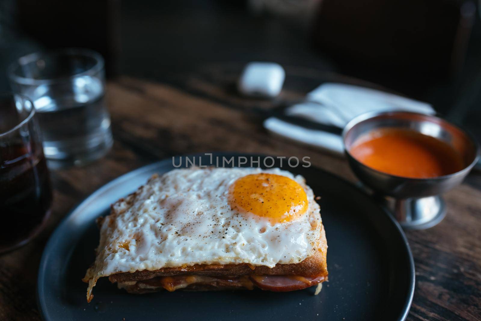 Toast with cheese and sausage covered with fried egg on a plate. Selective focus. Top view.