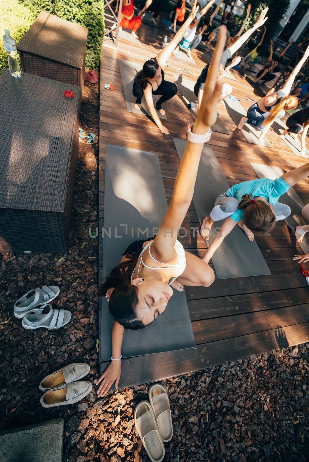 A woman does yoga together with her group in the open air by teksomolika