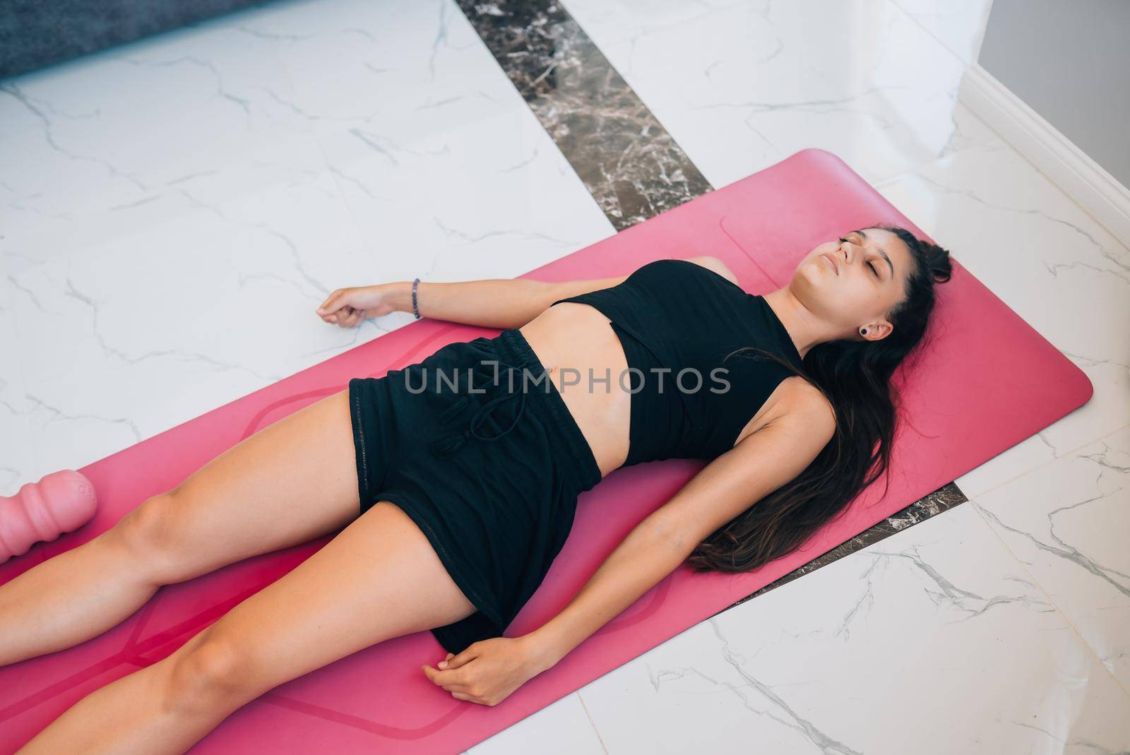 Young woman practicing in a yoga studio. Shavasana or corps pose is the end of a class or practice.
