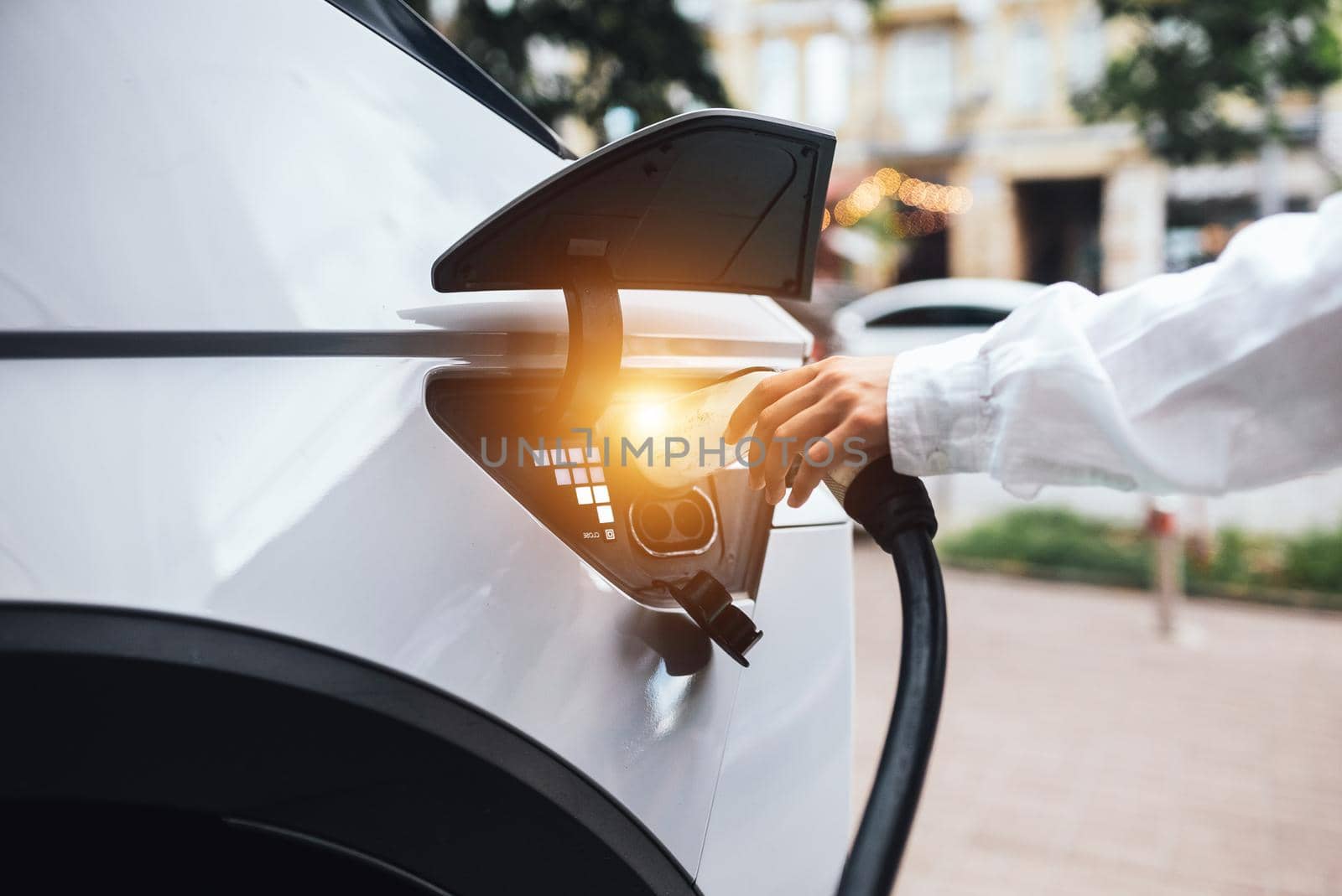 Human hand is holding Electric Car Charging nozzle. Selective focus on hand and nozzle