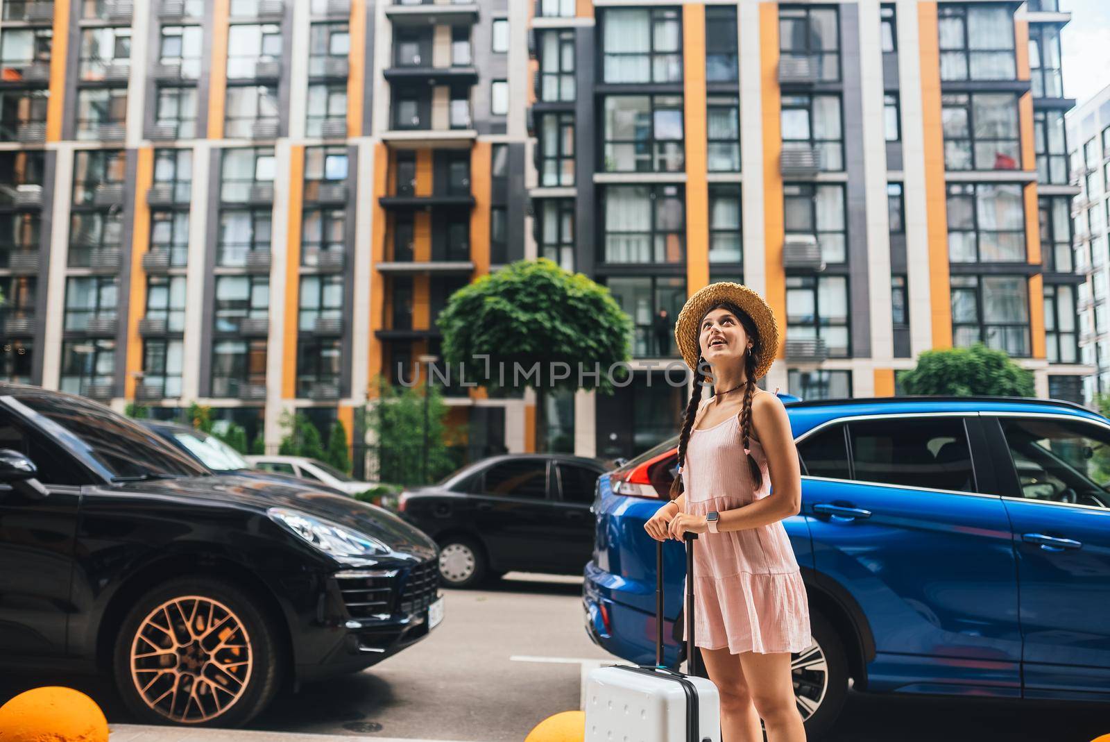 Young beautiful woman with a suitcase on the background of a modern city