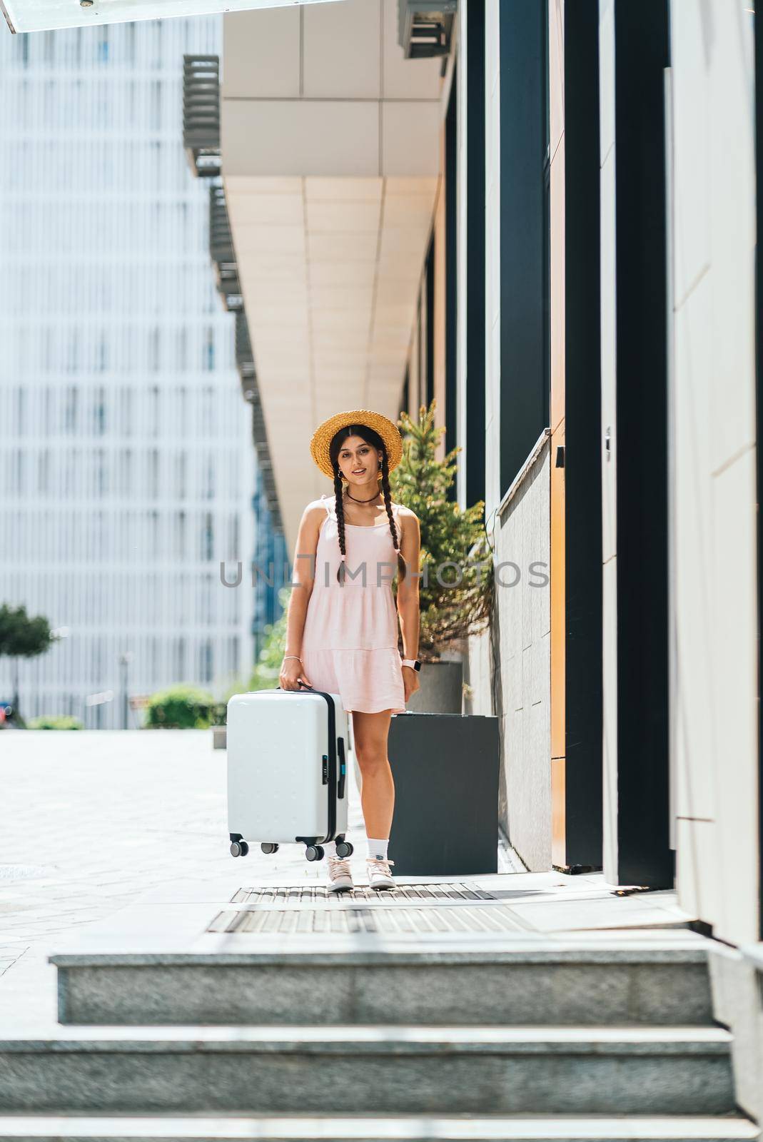 Young beautiful woman with a suitcase on the background of a modern city