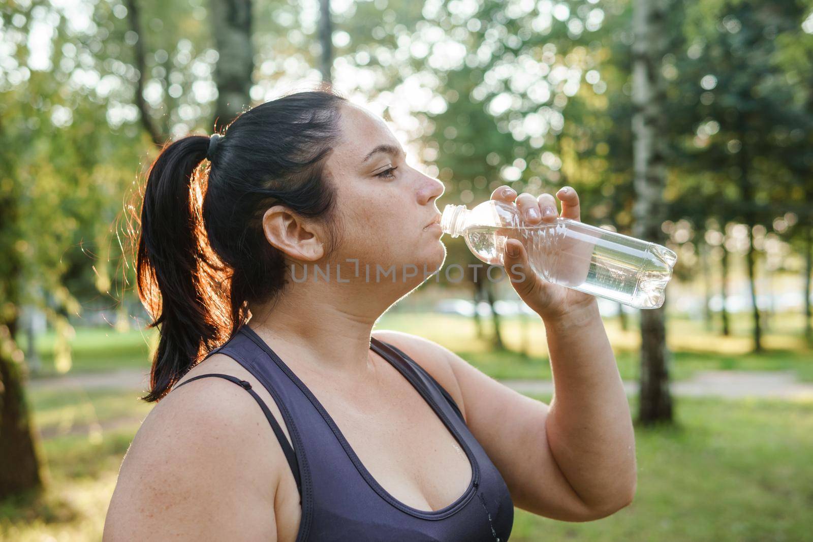 A charming brunette woman plus-size body positive practices sports in nature.