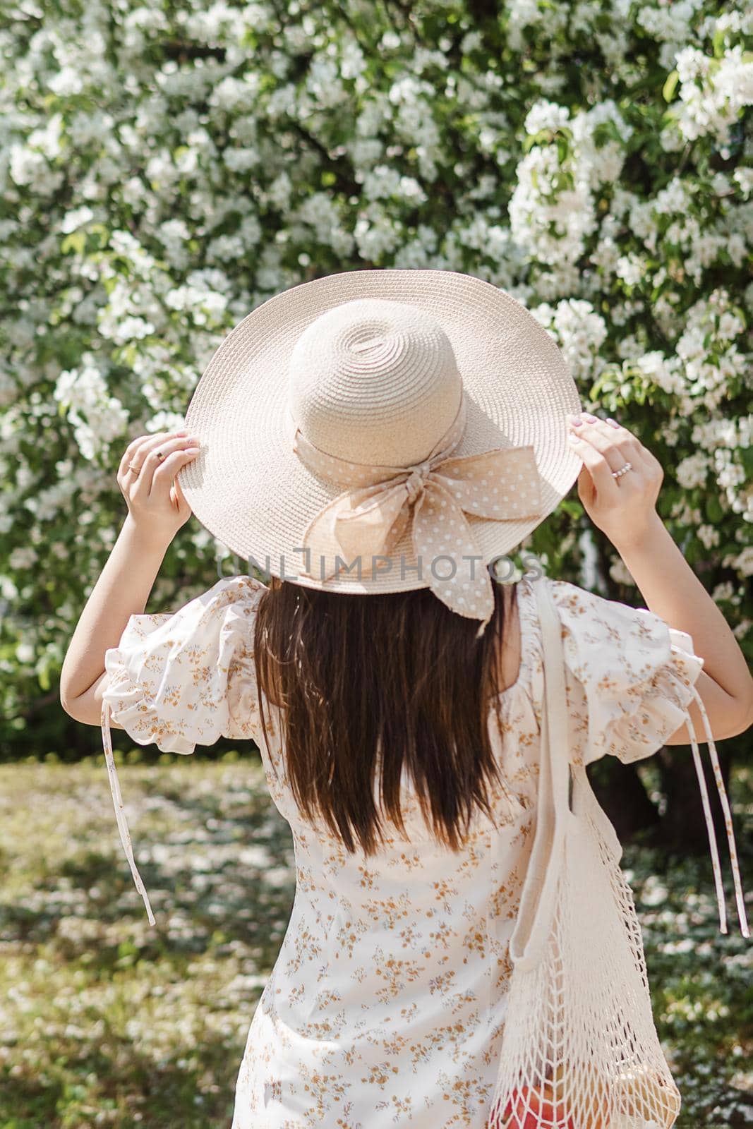 An attractive long-haired woman walks in the spring in the park of blooming apple trees. Spring portrait of a woman