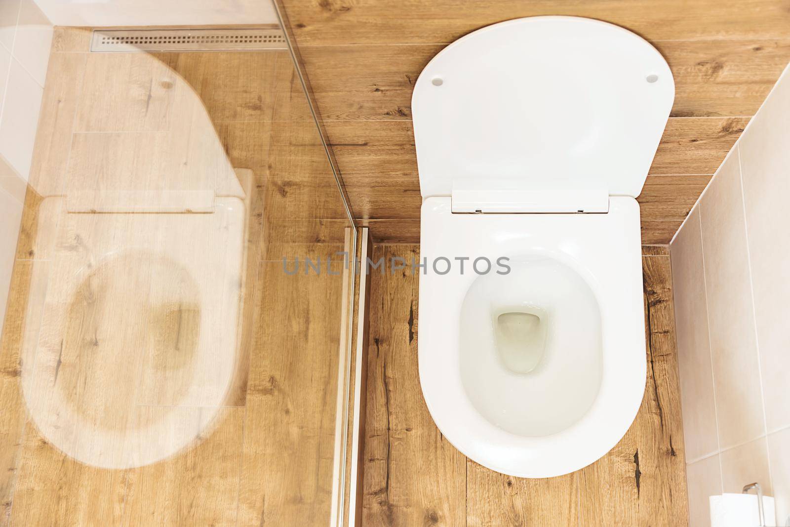 top view, clean white toilet bowl with open lid in modern bathroom, white walls and wooden floor by Ramanouskaya