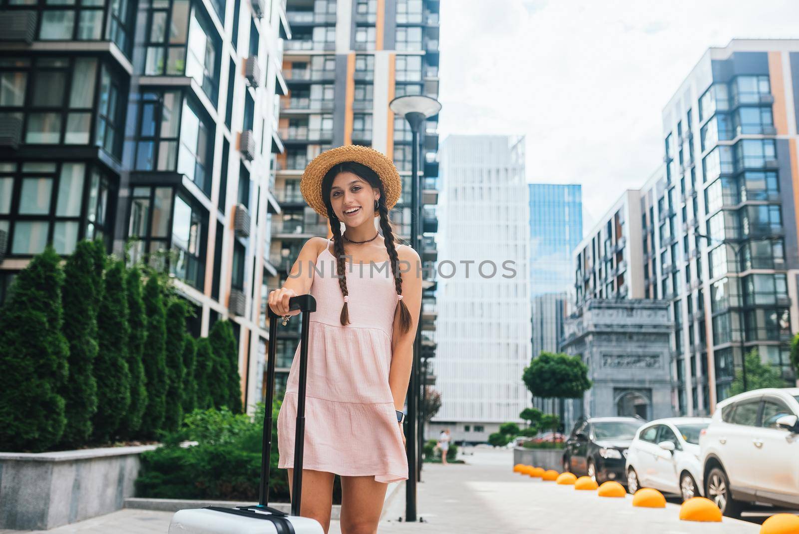 Young beautiful woman with a suitcase on the background of a modern city