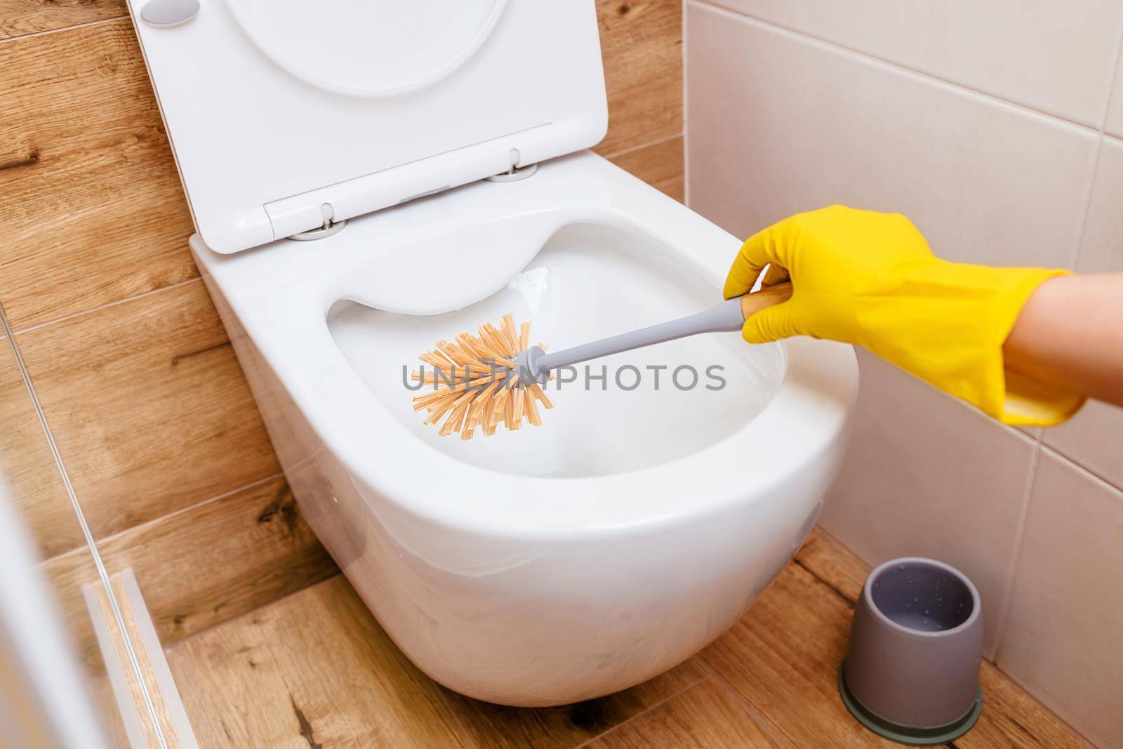 close-up of the bathroom Woman's hands in rubber yellow gloves with the help of a brush and powder cleans the toilet. The concept of cleaning, hygiene, disinfection. Copy paste for your design.