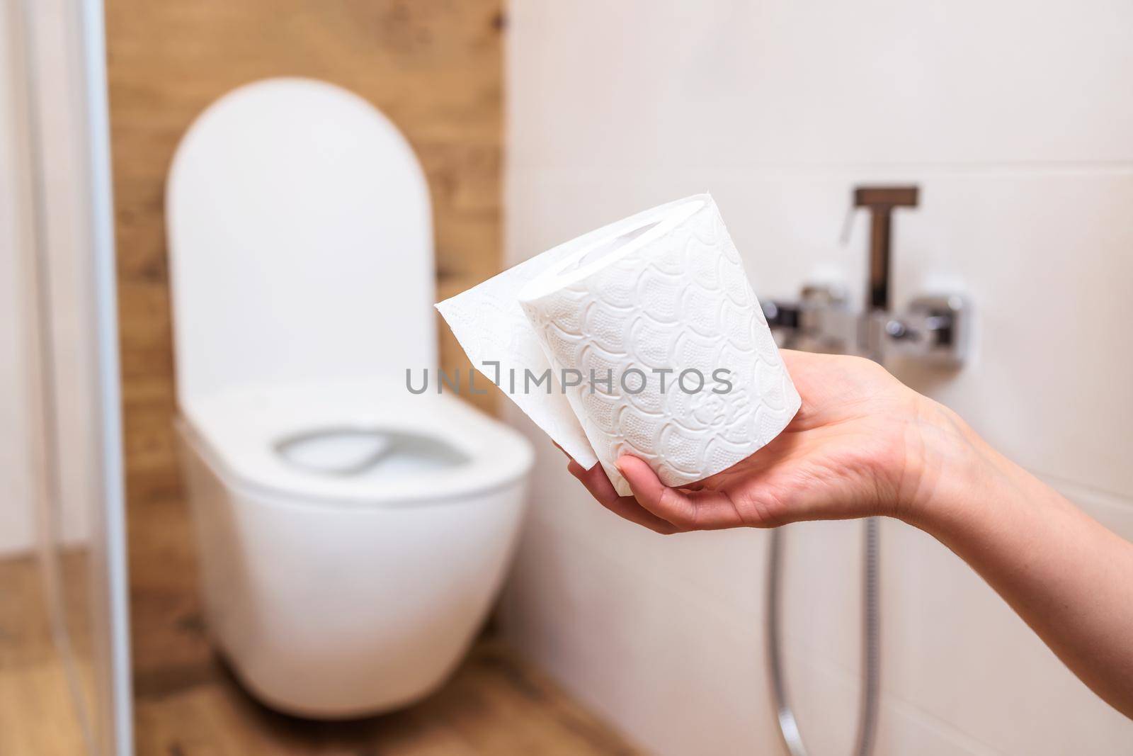 close-up, a roll of white toilet paper with a sad face on the background of the bathroom. The concept of feeling unwell, hemorrhoids, health, stomach disease. Personal hygiene and ecology.