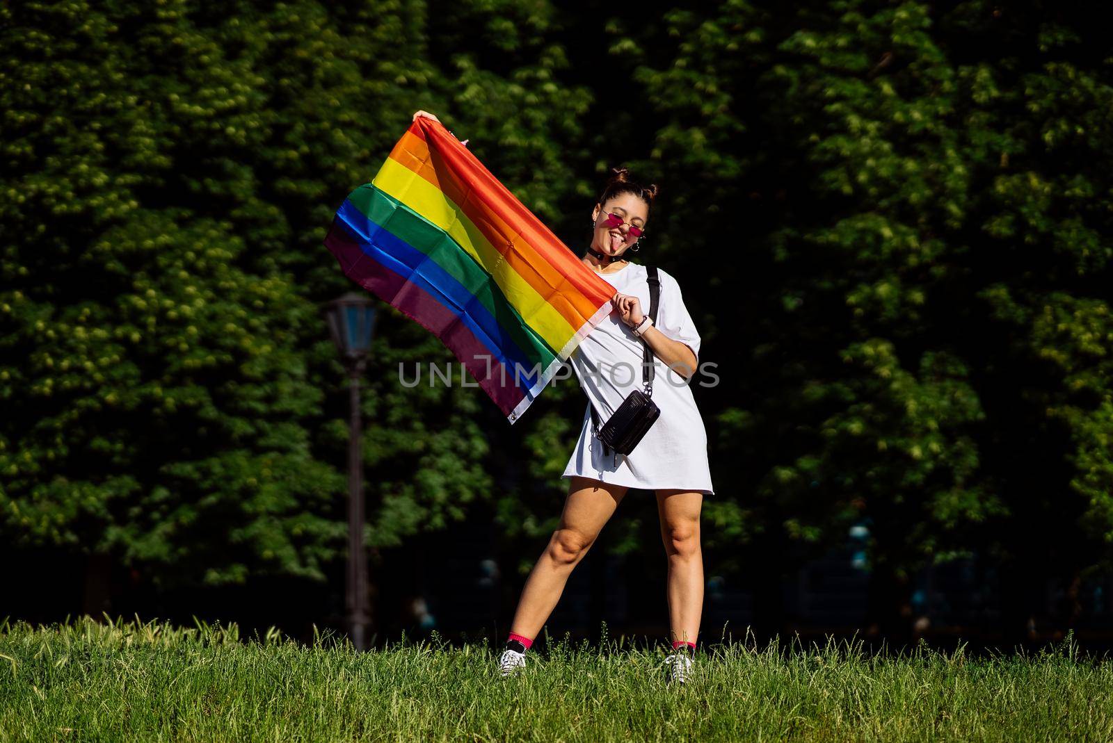 Young woman with lgbt pride flag in the park.