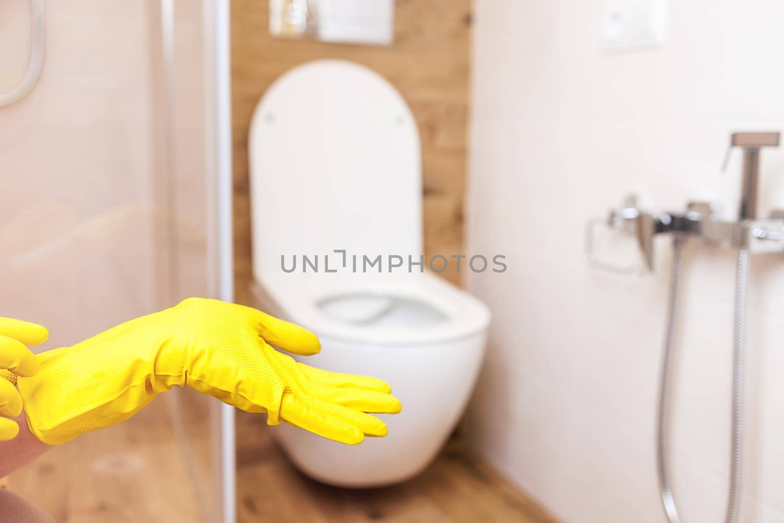 toilet cleaner mockup. Against the backdrop of the bathroom, close-up of female hands in protective gloves and copy-paste space for your design. The concept of cleaning and disinfection indoors