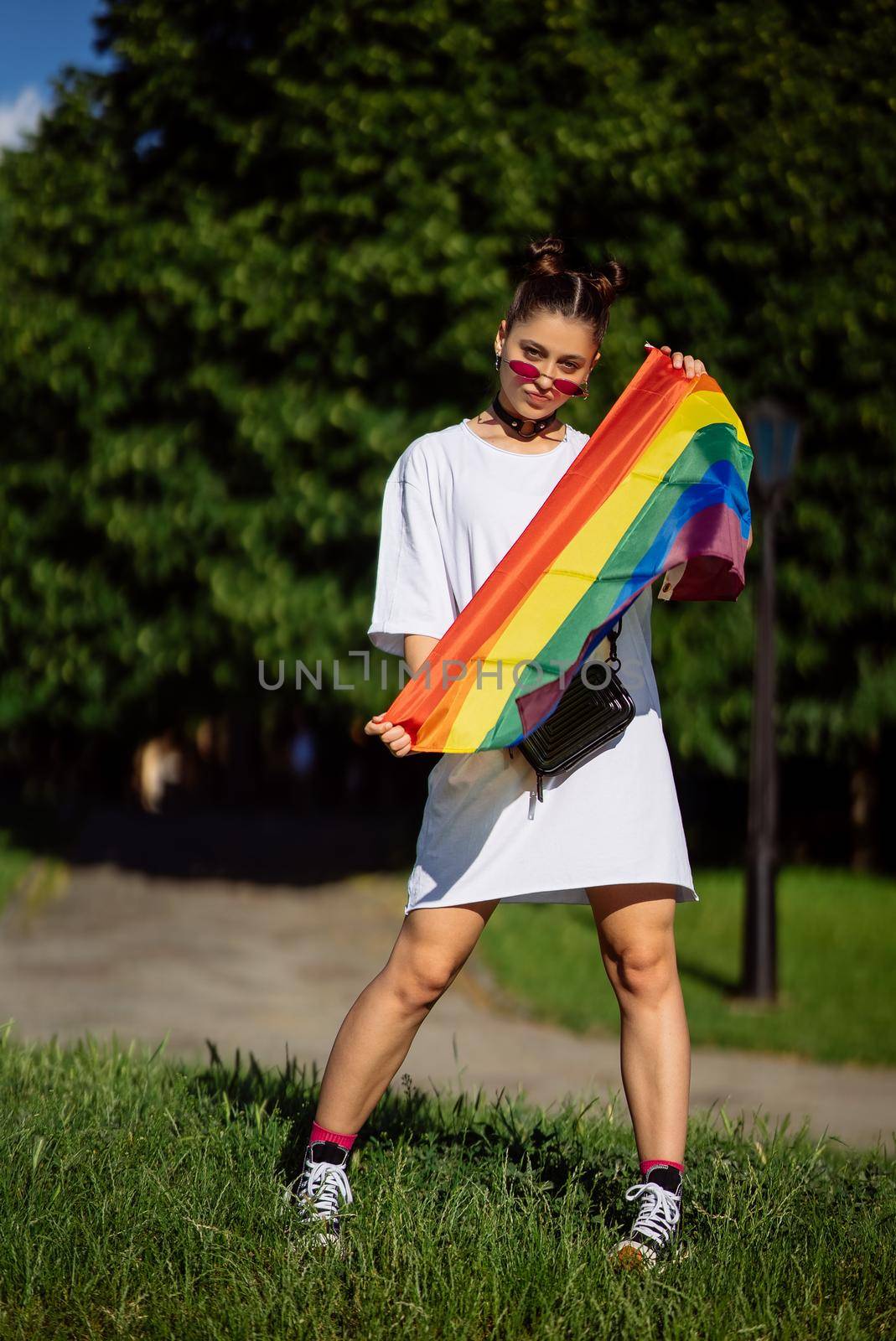 Young woman with lgbt pride flag in the park.