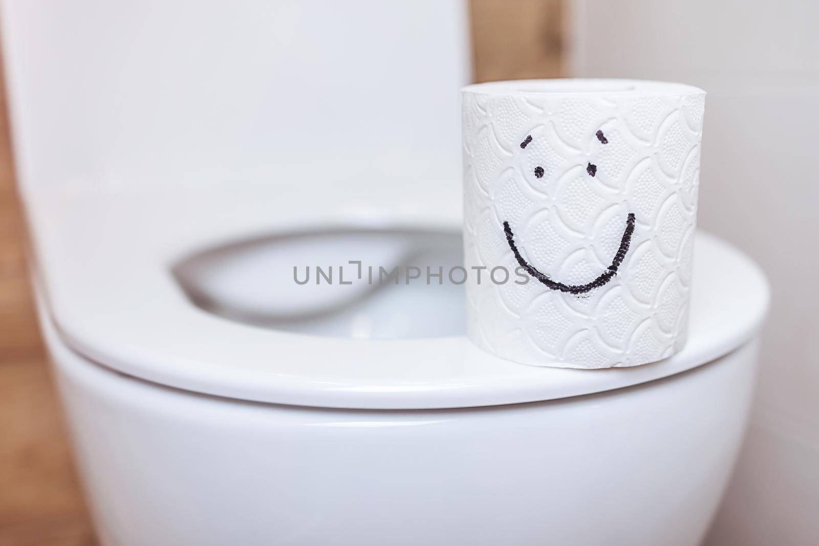 close-up of toilet paper with a painted happy face, on a toilet with an open lid by Ramanouskaya