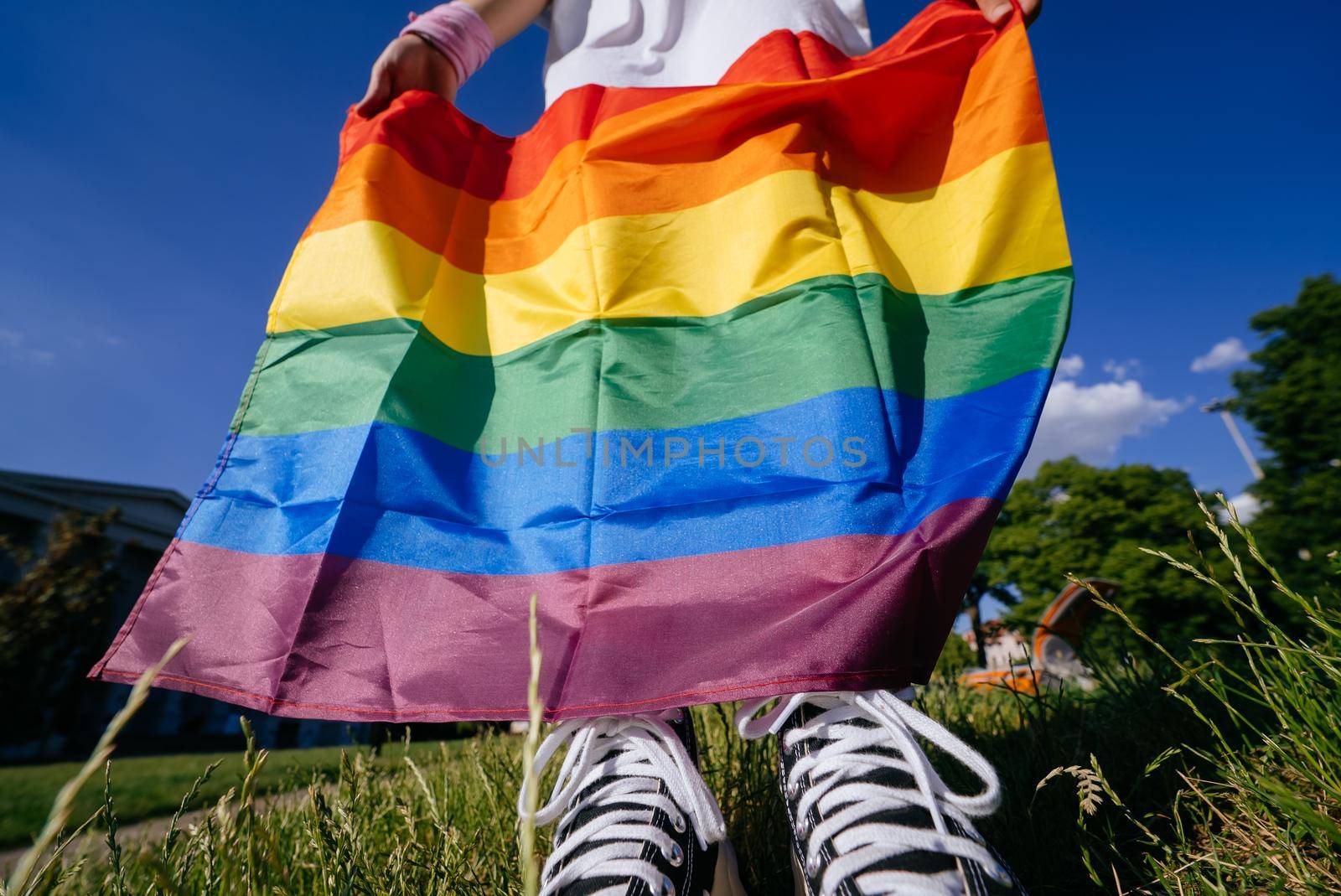 Young woman holding an LGBT pride flag in her hands. Close view, cropped photo