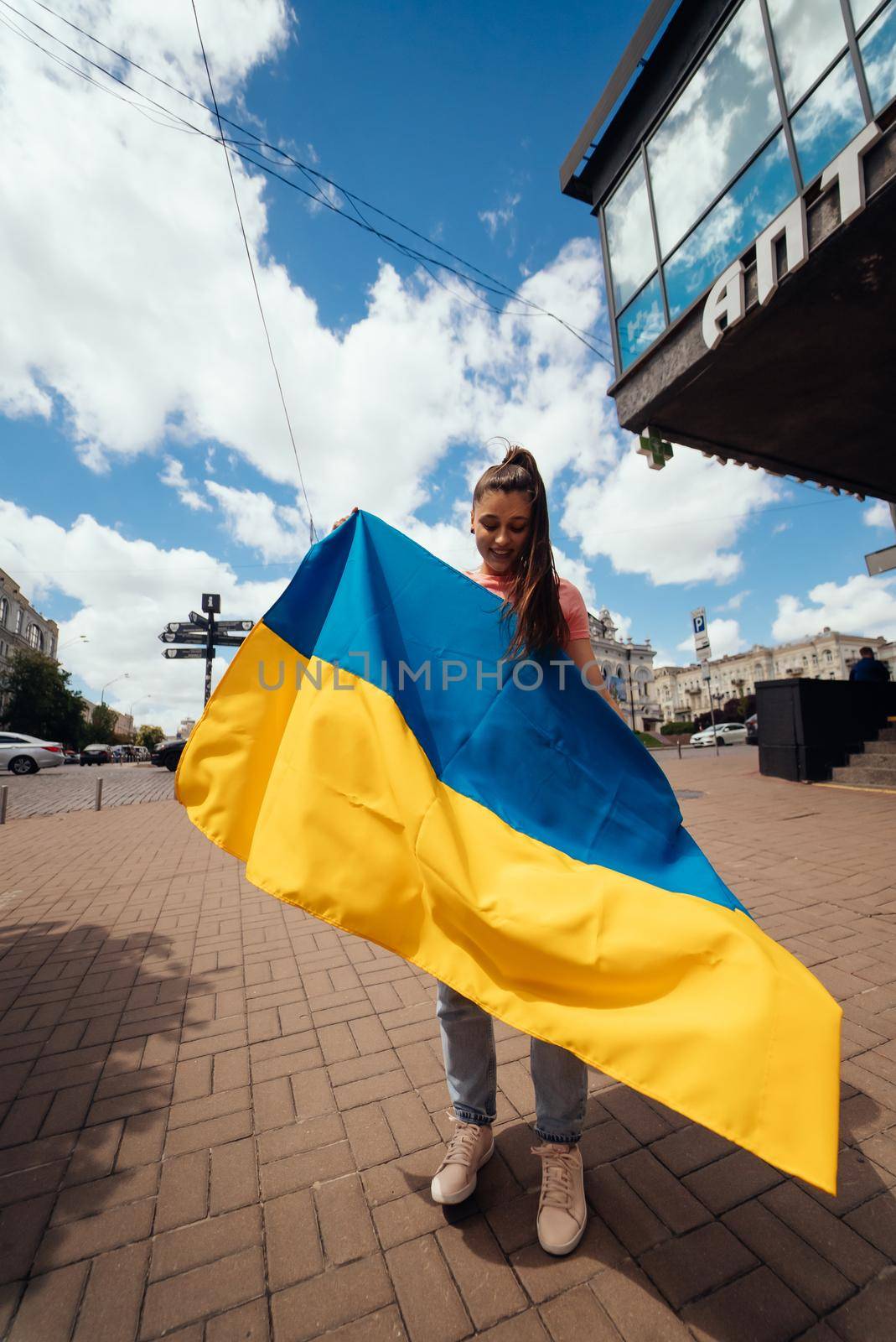 Young woman with national flag of Ukraine walking in the city