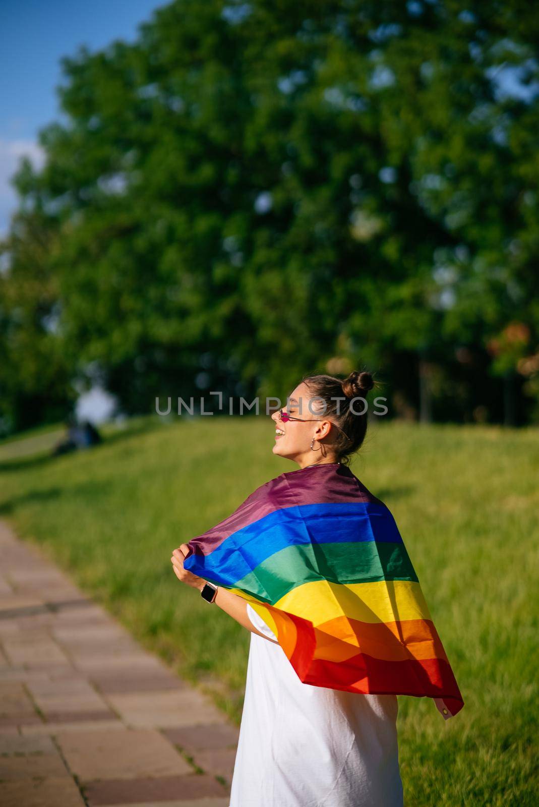 Young woman with lgbt pride flag in the park.