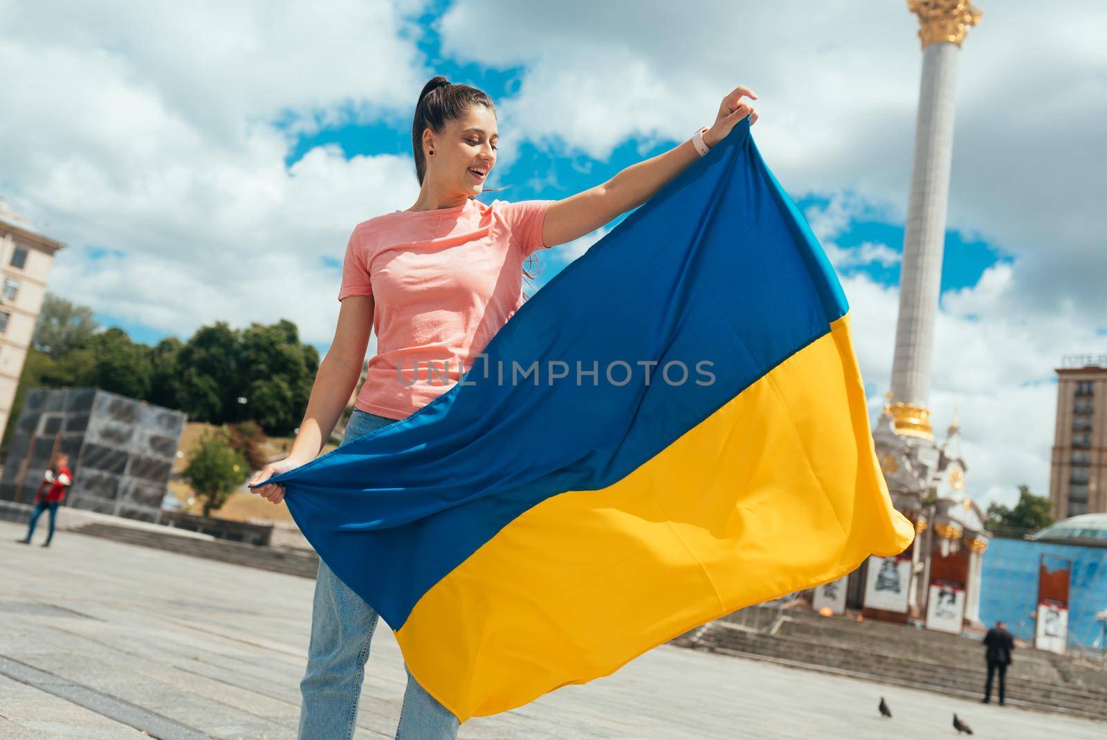 Young woman holding national flag of Ukraine in the city