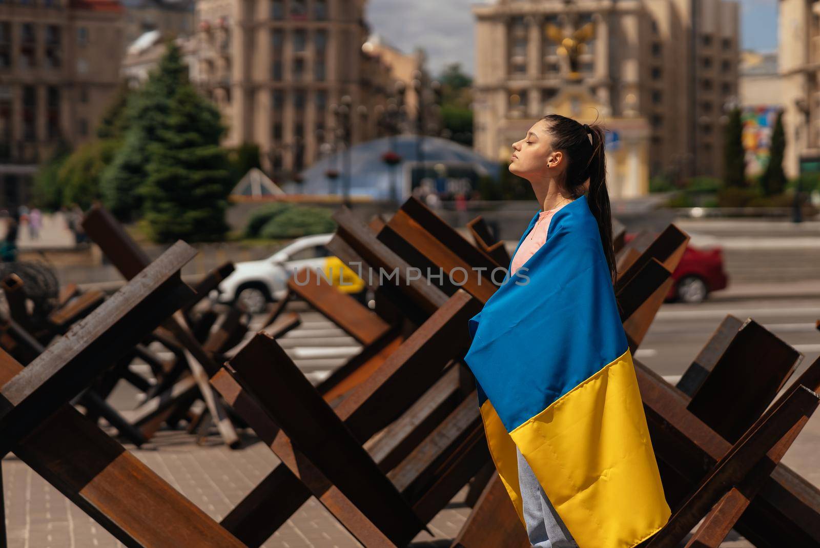 Young woman with national flag of Ukraine walking in the city