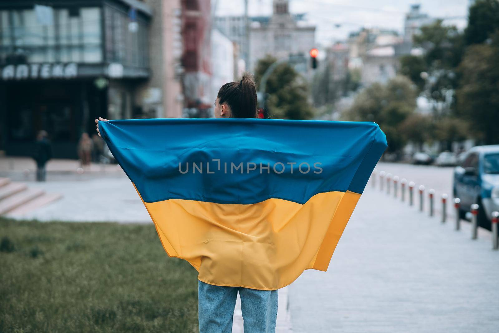 Young woman with national flag of Ukraine walking in the city