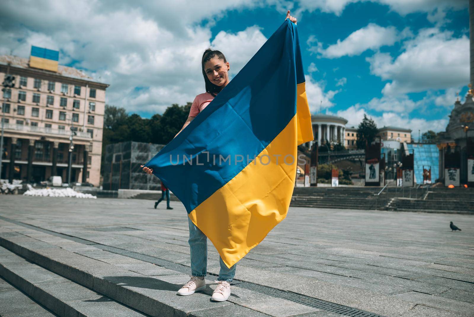 Young woman holding national flag of Ukraine in the city