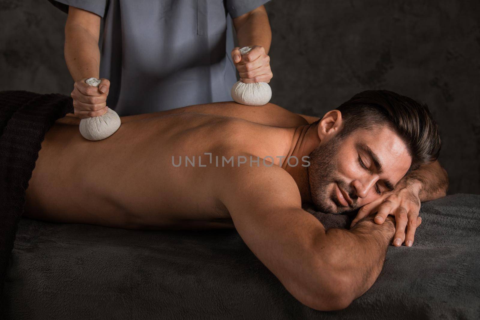 Young handsome man having back massage with pouche