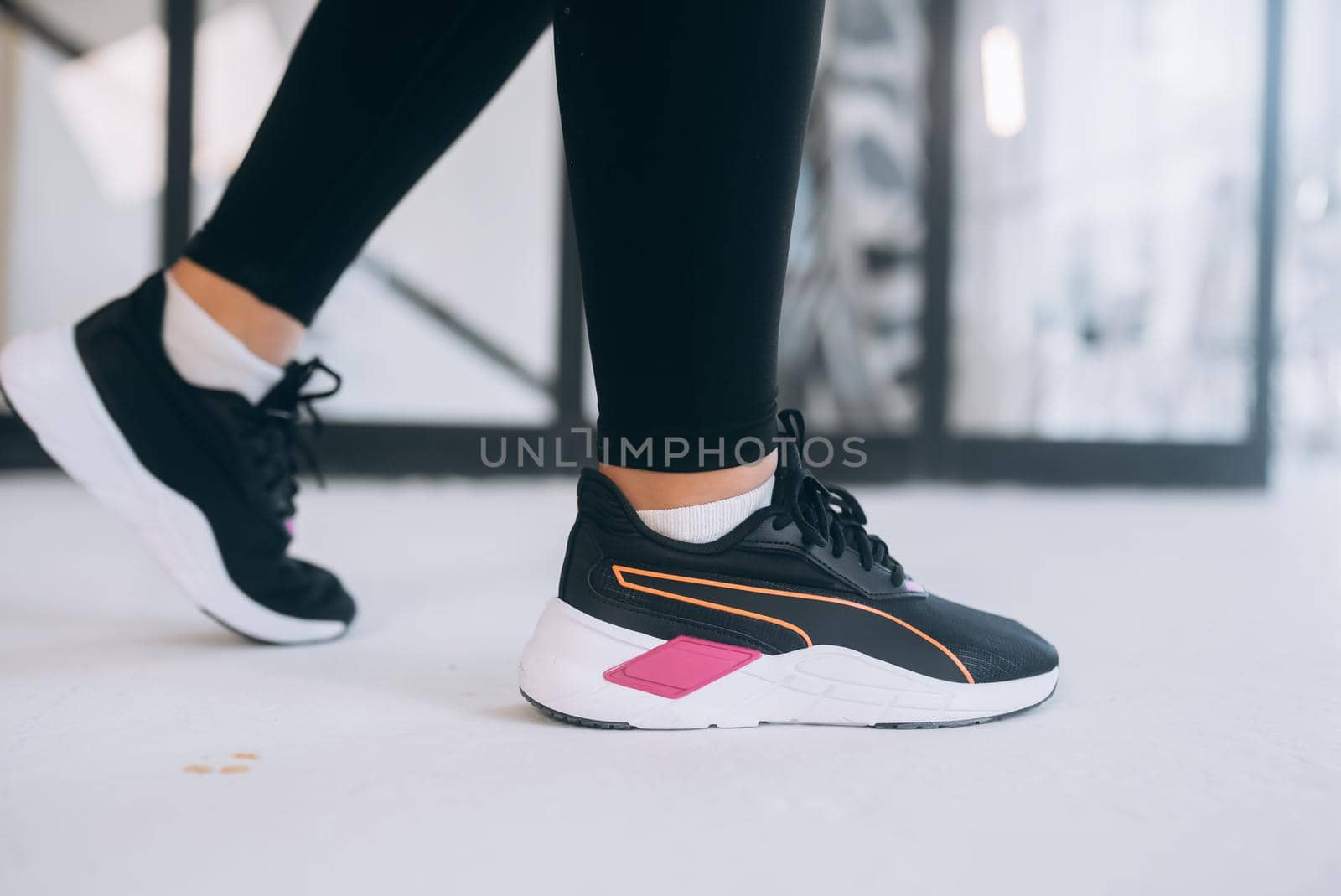 Female legs in sneakers close up indoors. Legs with unbranded sport shoes