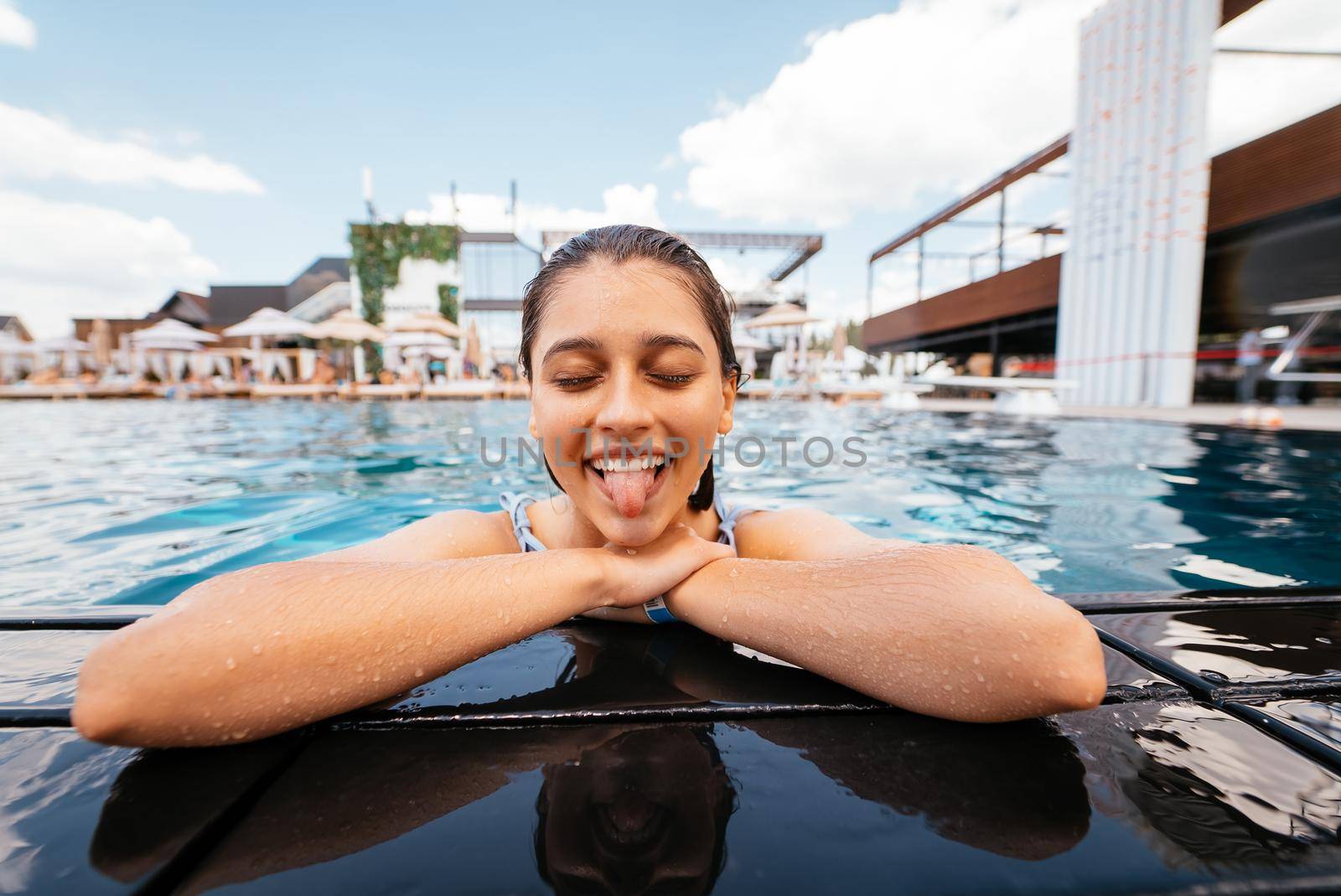Beautiful young woman resting on the edge of swimming pool