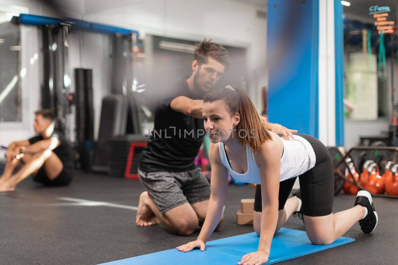 A female trainee exercises while being coached by her personal trainer at the crossfit box