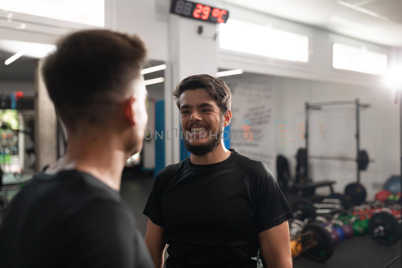 Two personal trainers smiling at each other at their workplace in the crossfit box