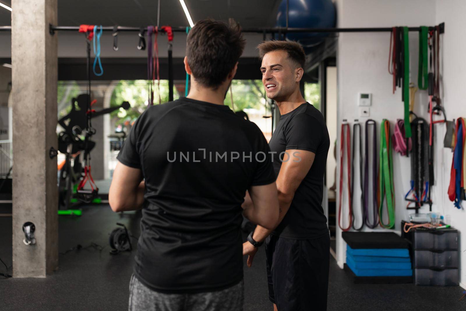 Two personal trainers talking to each other at the gym by stockrojoverdeyazul