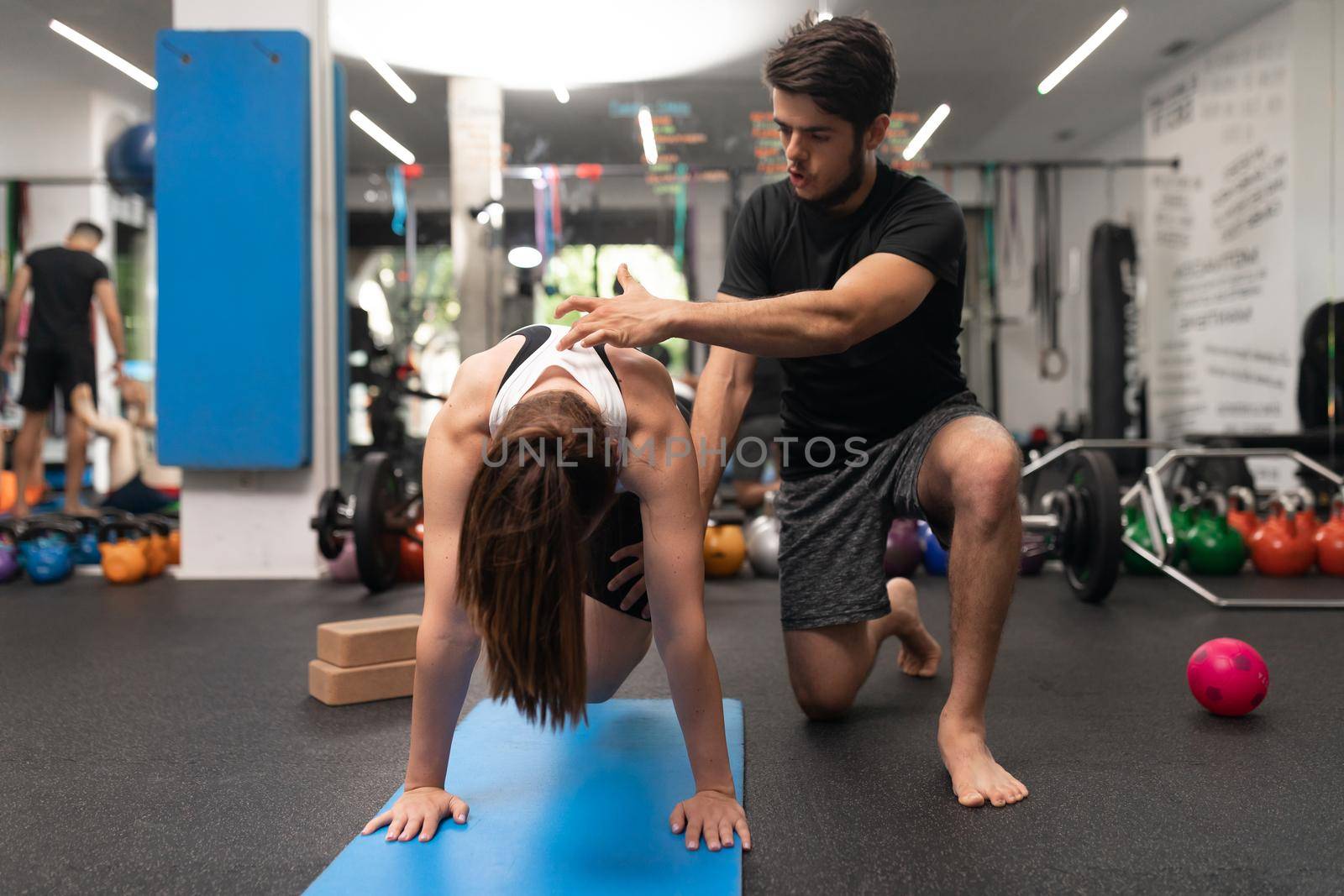 A coach correcting the posture of a female trainee during a training session at the gym