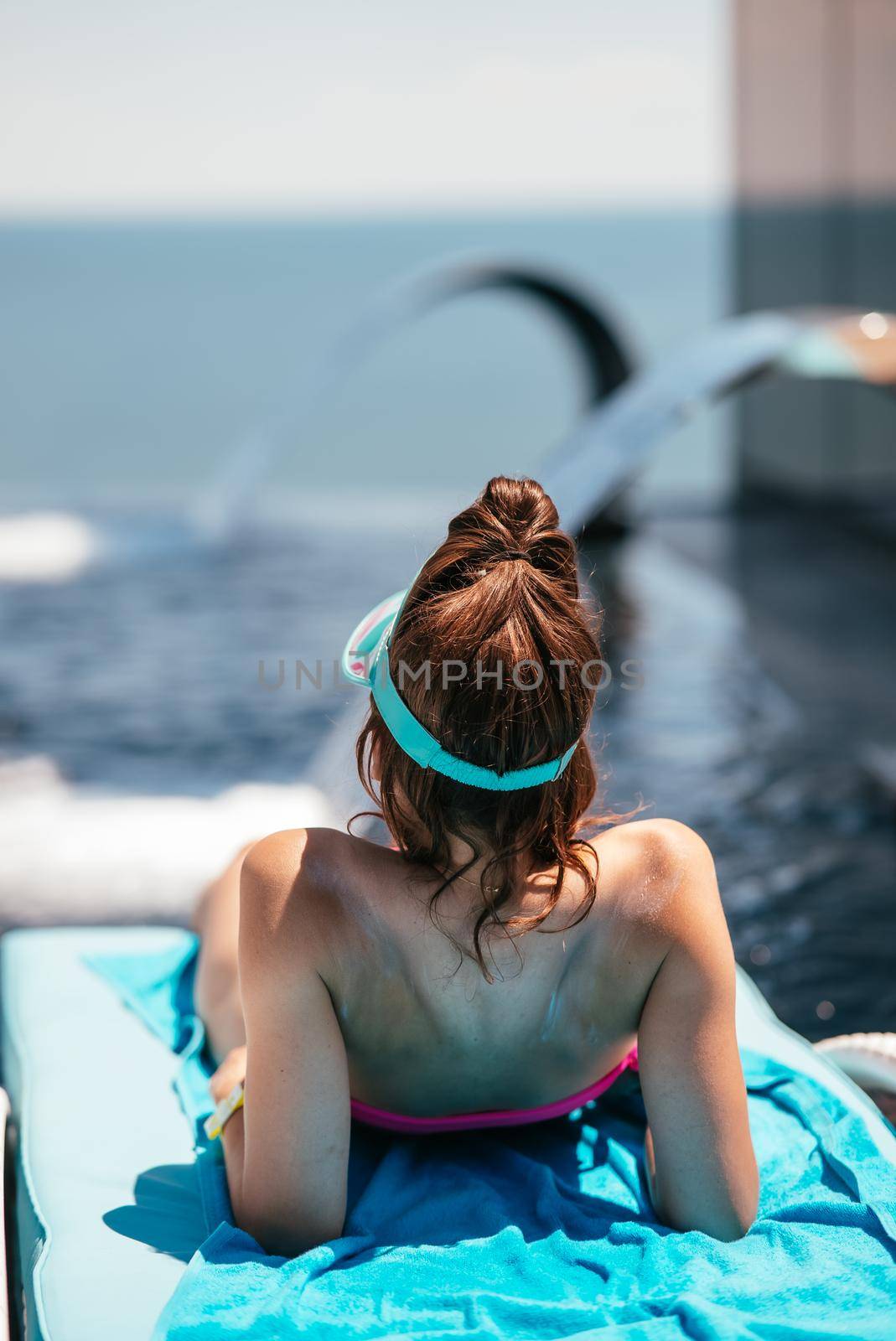 A young beautiful woman in swimsuit sunbathes on a sun lounger by the pool at the hotel.Summer concept.