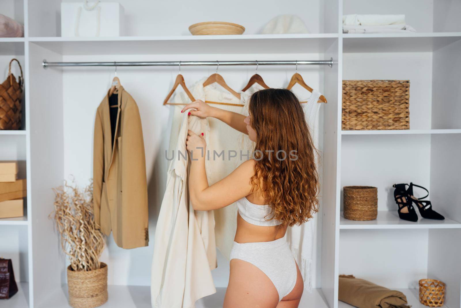 Young woman in white lingerie chooses clothes at home