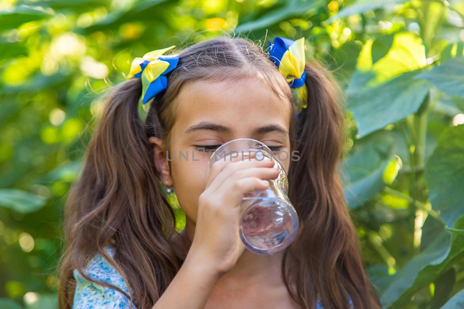 The child drinks water from a glass. Selective focus. Kid.