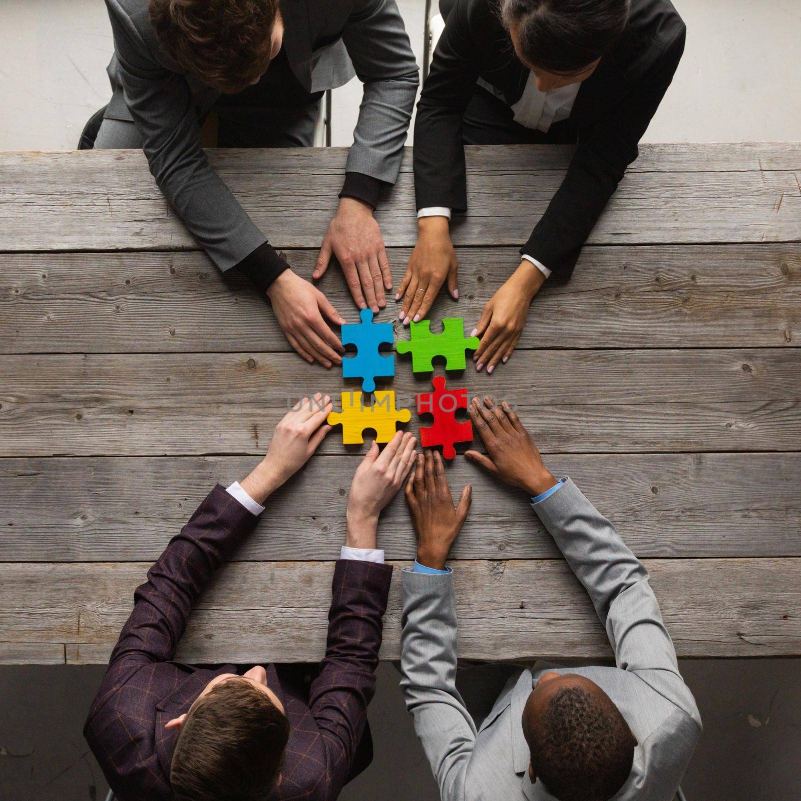 Diverse team people assembling jigsaw puzzle, multiracial group of black and white colleagues engaging in successful teamwork finding business solution, corporate unity teambuilding concept, top view