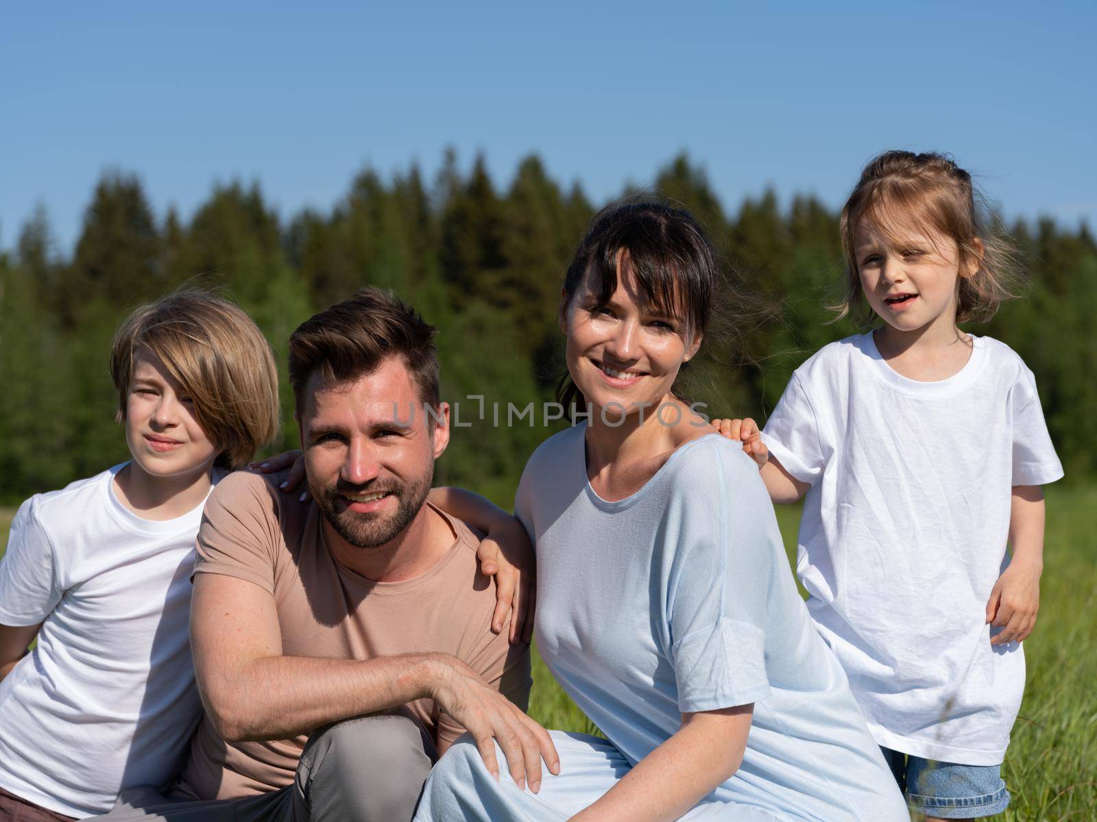 Happy beautiful young family of parents and children on summer meadow