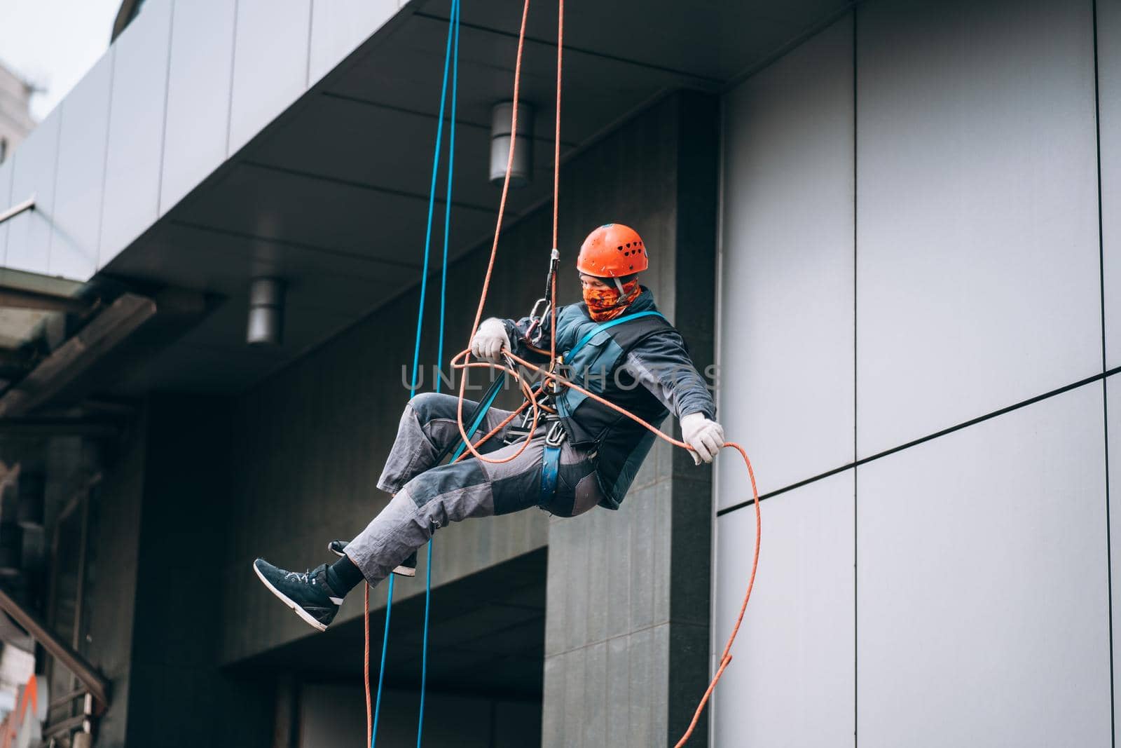 Industrial climber in uniform and helmet rises. Outdoor