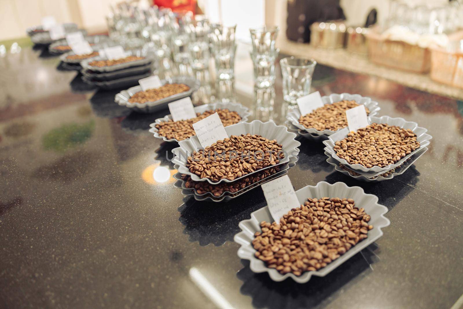 Different varieties of coffee beans in plastic bowls and notes for tasting