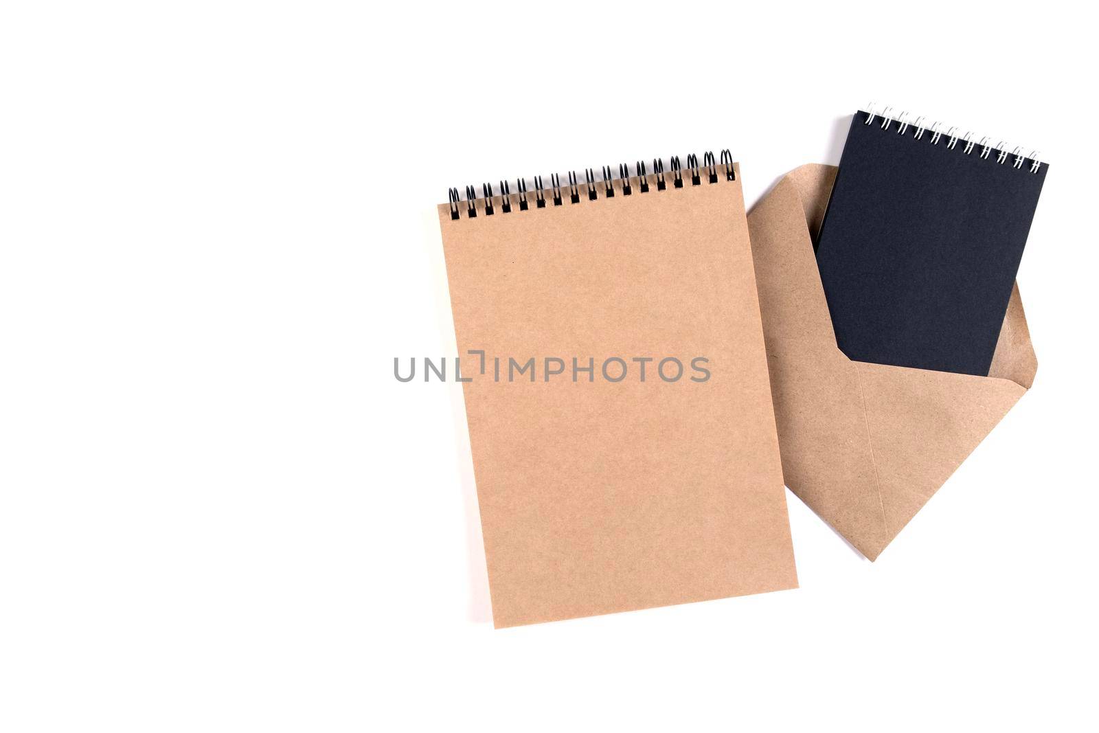 Blank spiral notepads and a recycled envelope stacked on a white background. Education, office, environmental protection, zero waste.