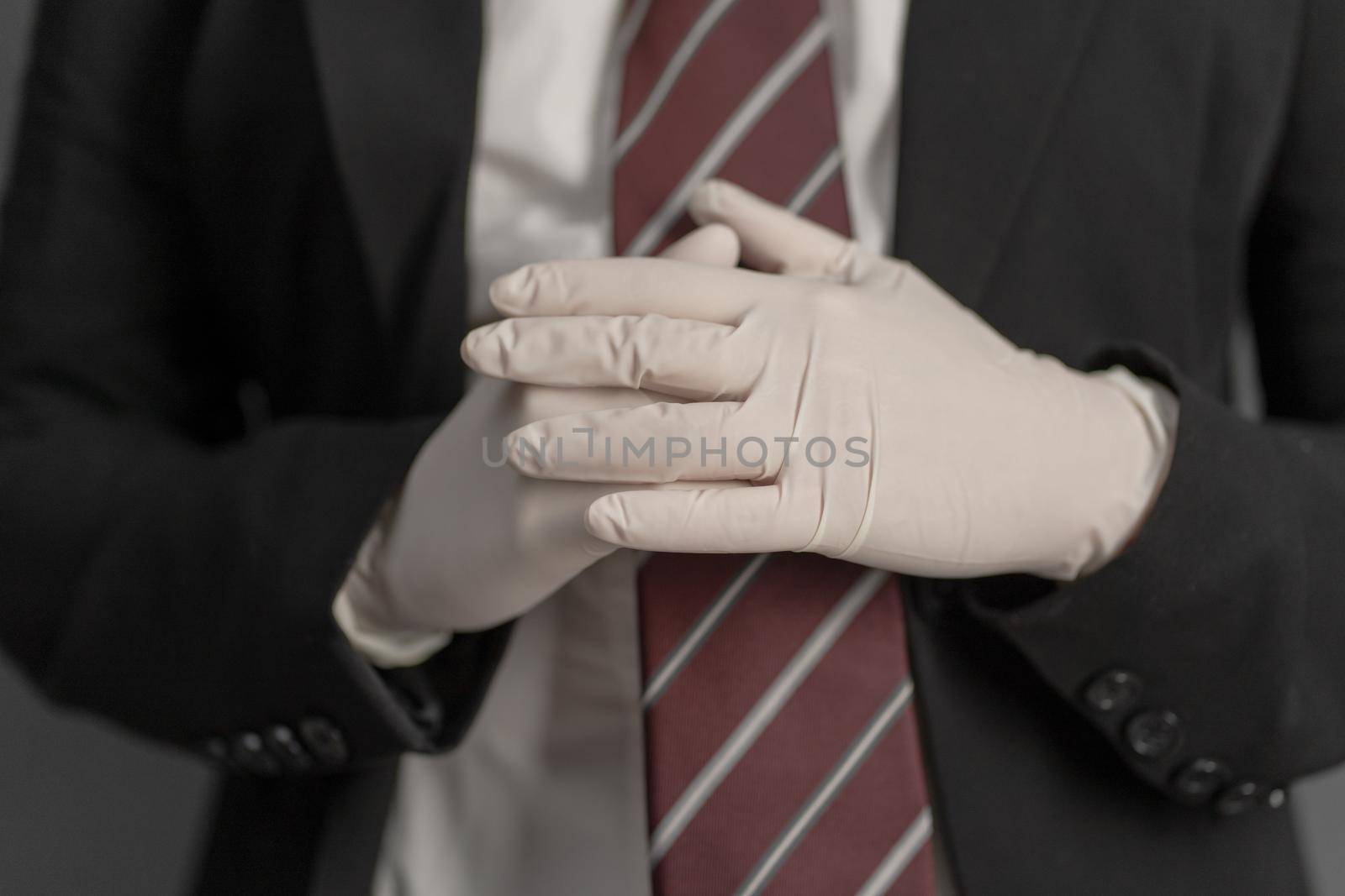 Businesswoman putting on disposable gloves. Selective focus on female hand in foreground. Preventive measures concept. Close up shot.