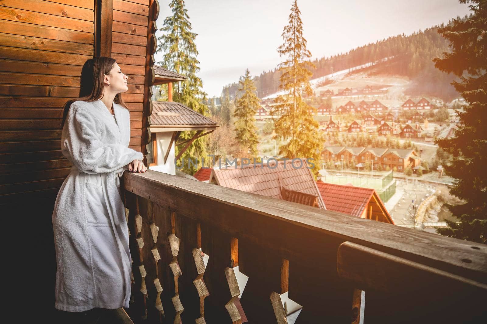 The girl is standing on a terraced house in a mountainous area. In good winter weather.