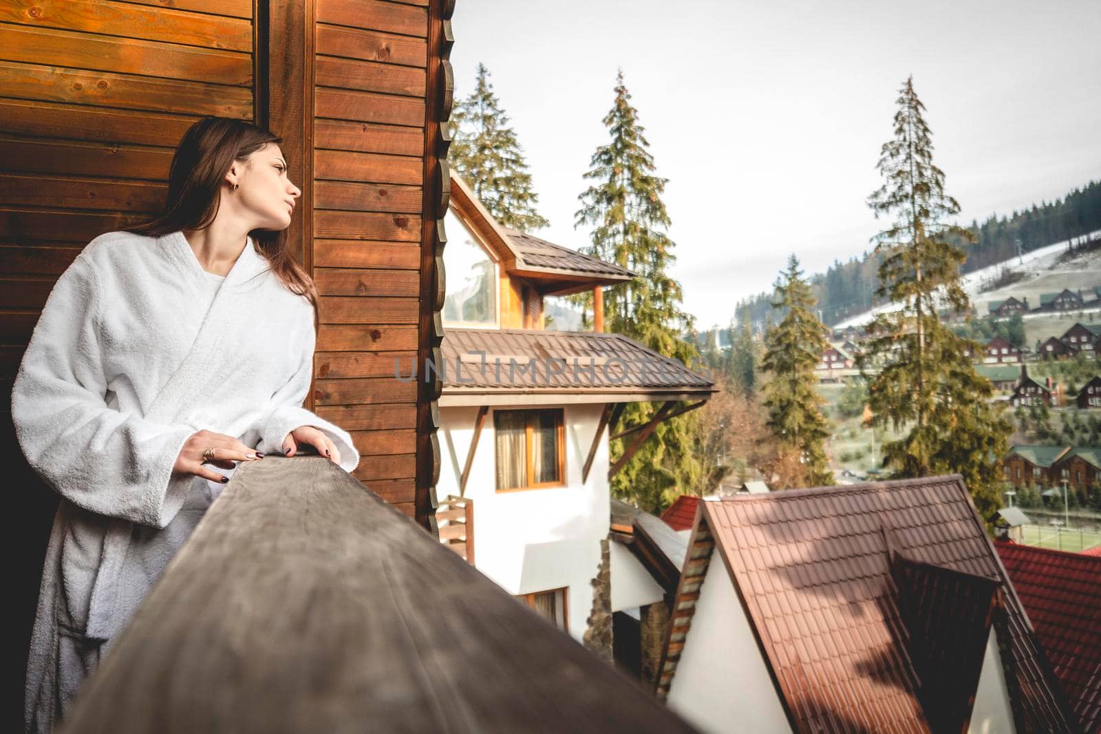 The girl is standing on a terraced house in a mountainous area. In good winter weather.